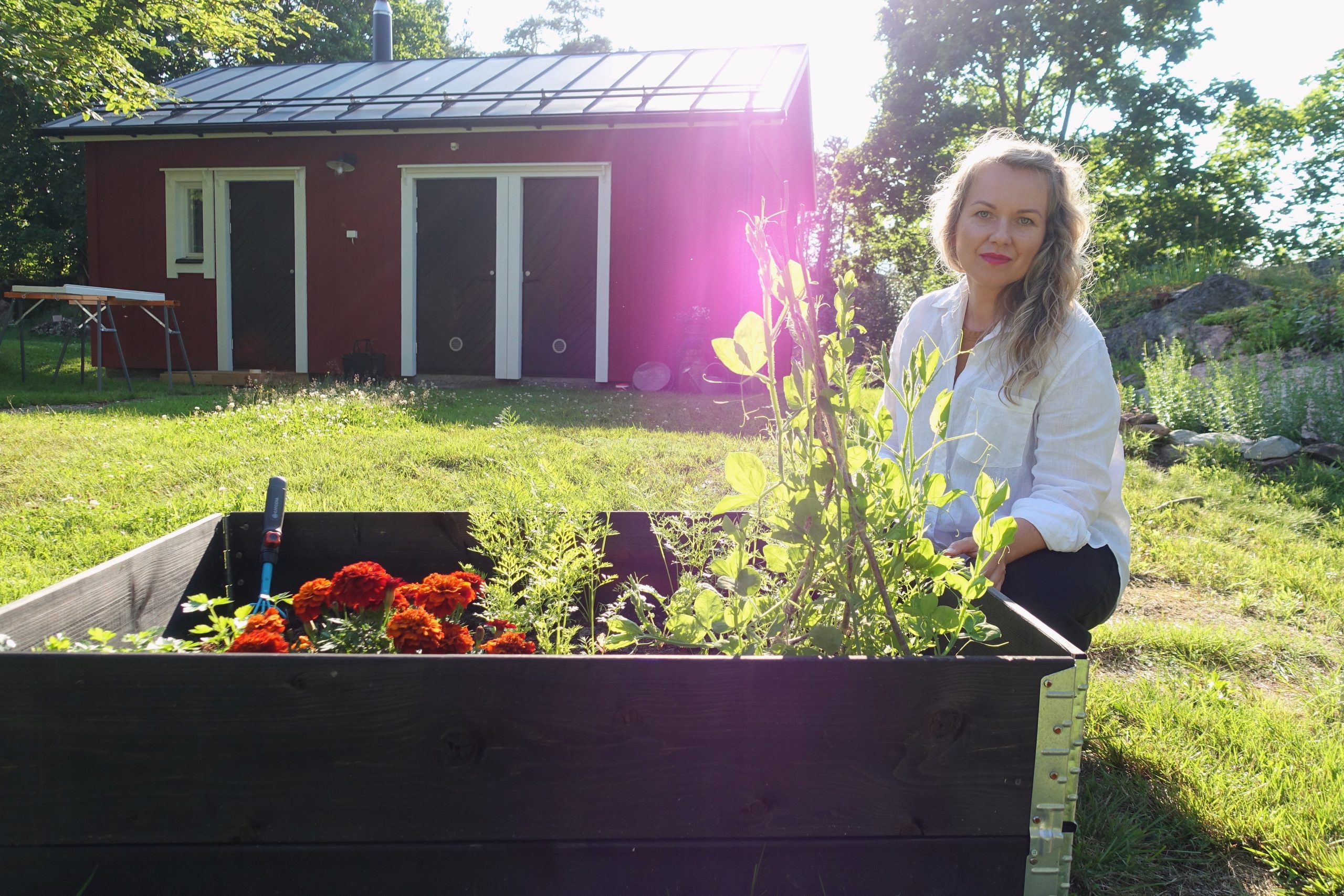 Hilma Ruokolainen kyykistyneenä viljelylaatikon taakse